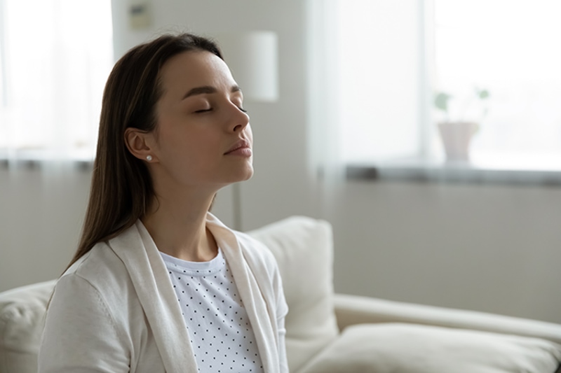 Why Do I Need a Humidifier? Image is a photograph of a woman with her eyes closed taking a deep breath.